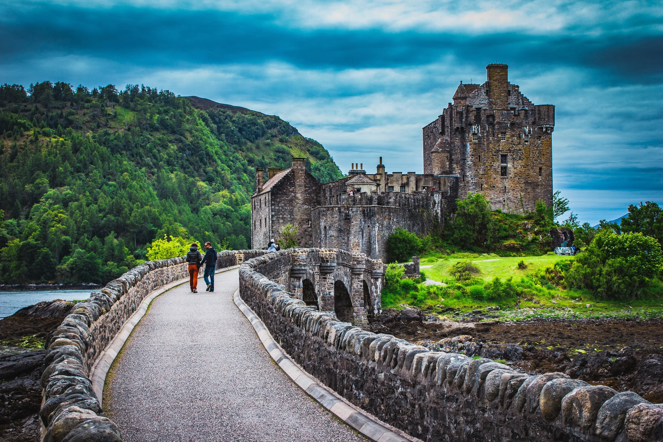 Eilean Donan Castle on its island, reached by a stone bridge, with Highland hills behind